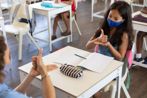 child with teacher signing help