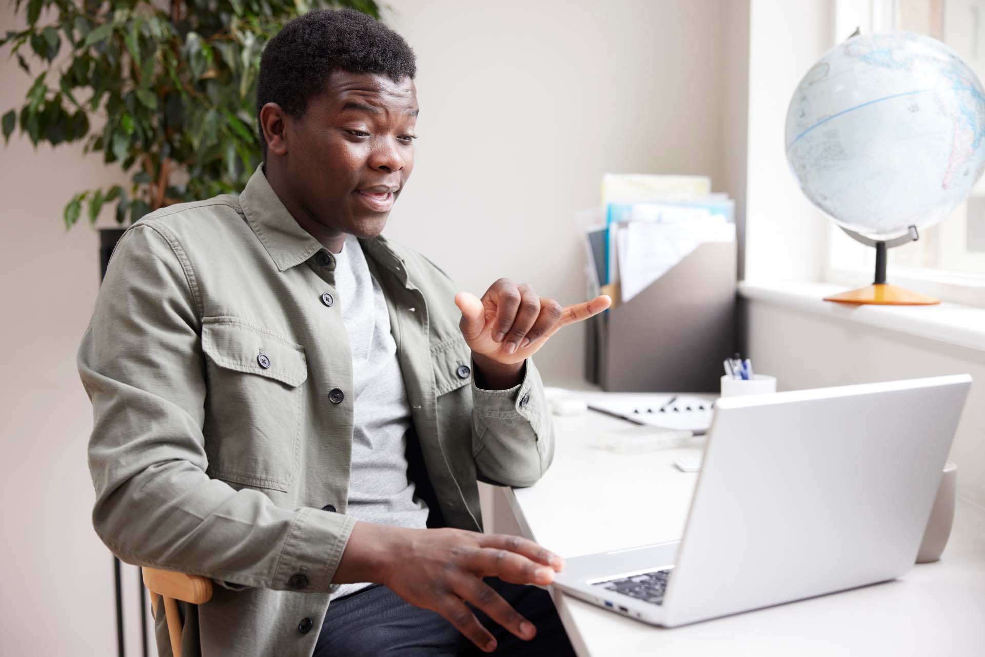 Black man signing in front of laptop